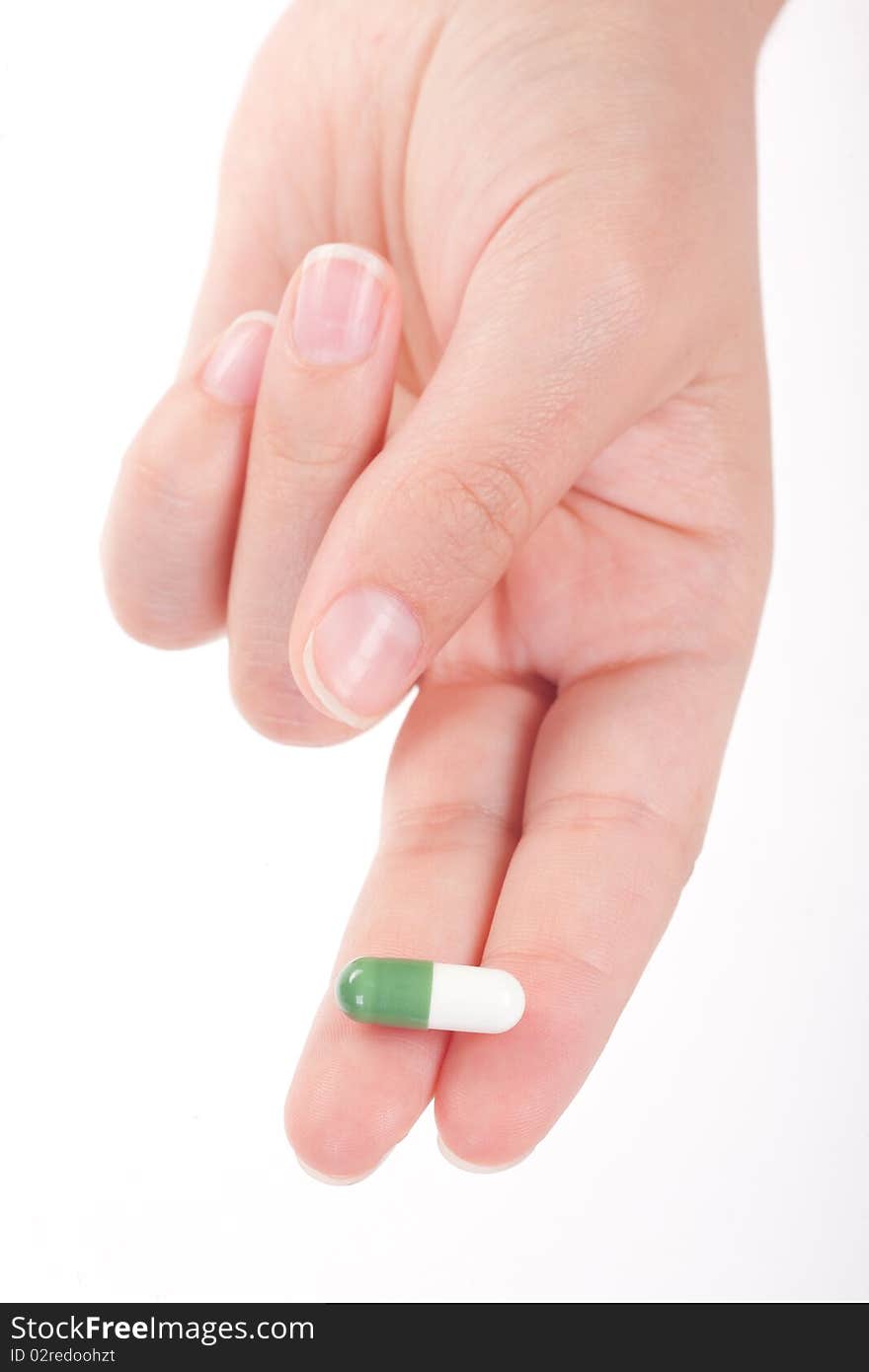 Green medical capsule in a female hand, isolated on white