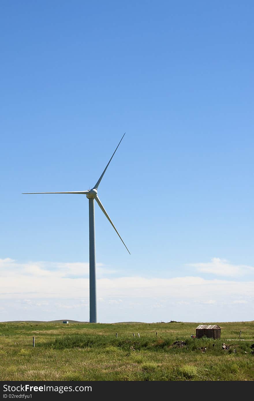 The white wind turbine generating electricity on blue sky. The white wind turbine generating electricity on blue sky