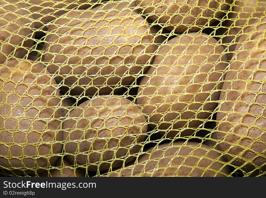 A yellow mesh bag of russet potatoes.