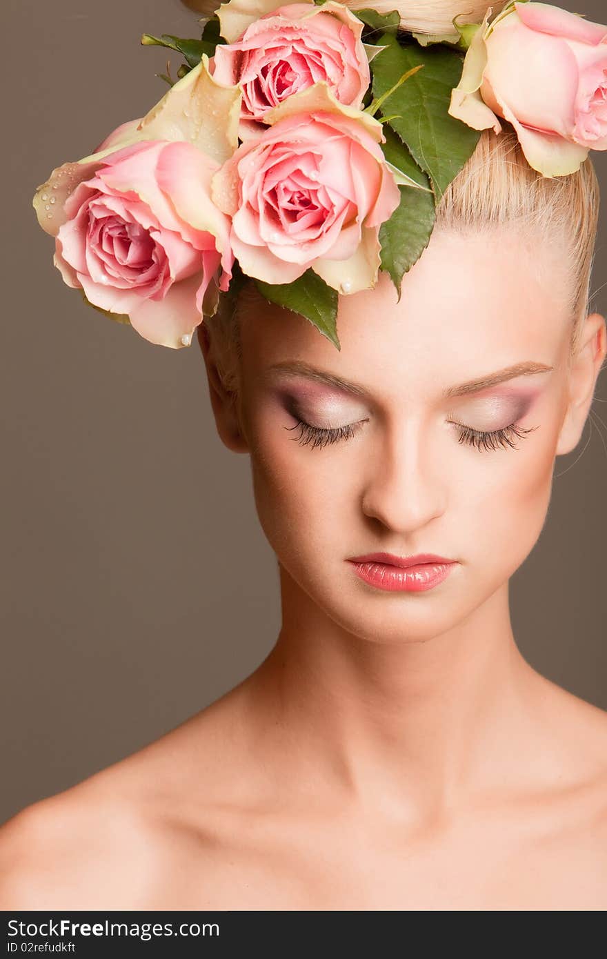 Portrait of beautiful blonde with a wreath of flowers on her head on the grey background