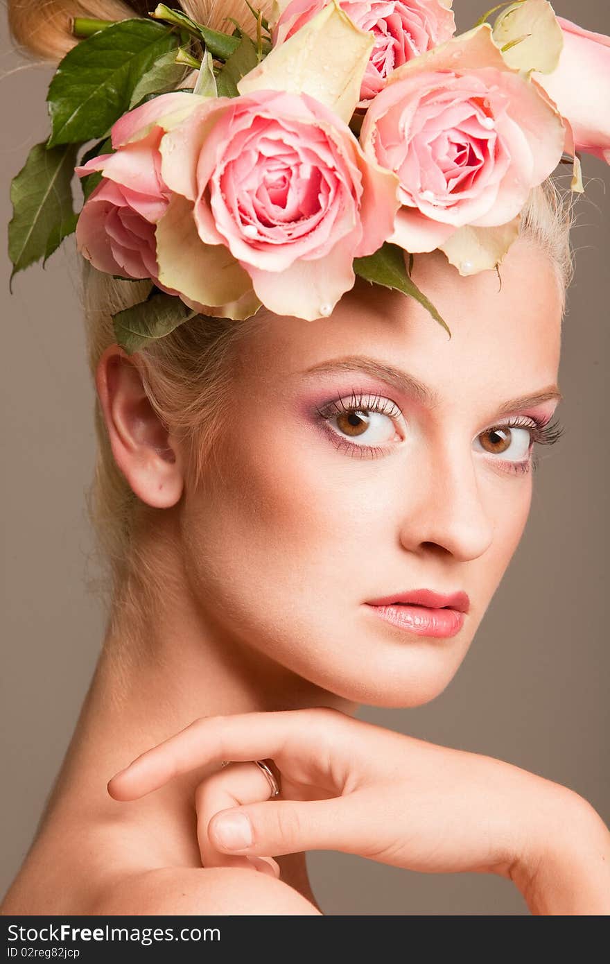 Portrait of beautiful blonde with a wreath of flowers on her head on the grey background