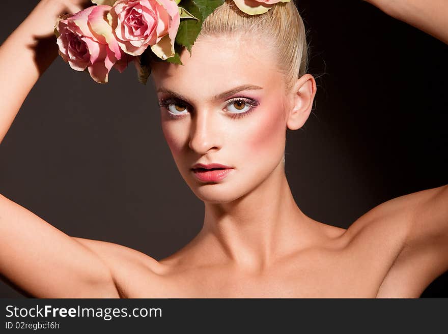 Portrait of beautiful blonde with a wreath of flowers on her head on the black background