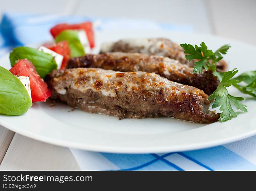 Roasted stuffed pork rolls served with tomatoes and feta