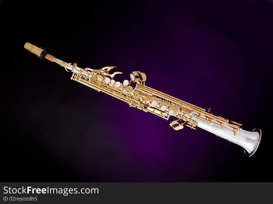 A professional soprano saxophone isolated against a spotlight purple background. A professional soprano saxophone isolated against a spotlight purple background.