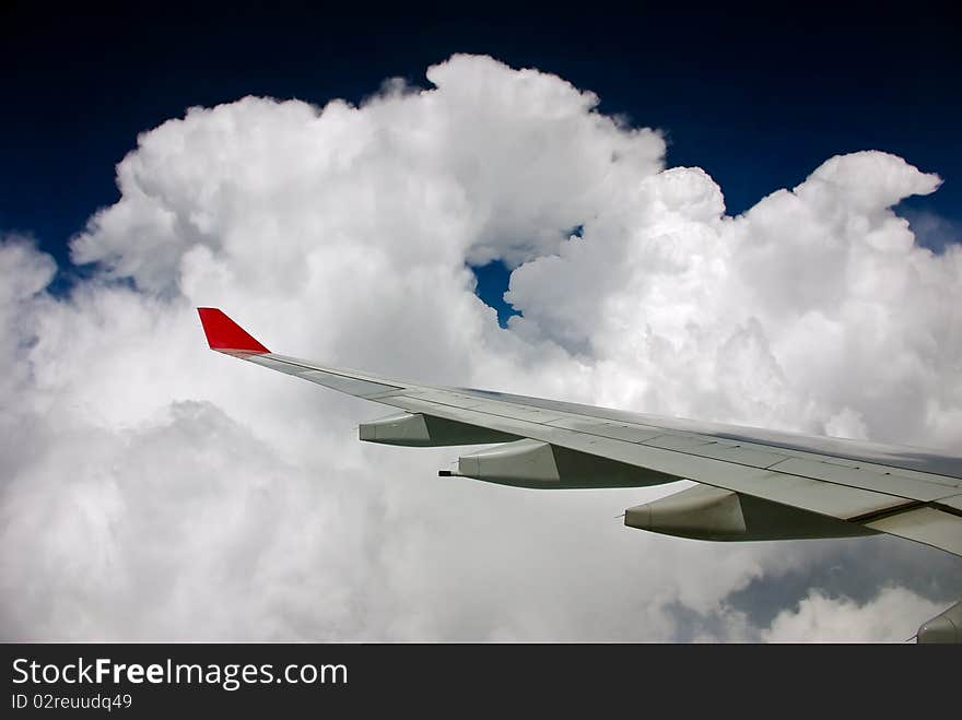 Airplane wing in clouds and blue sky