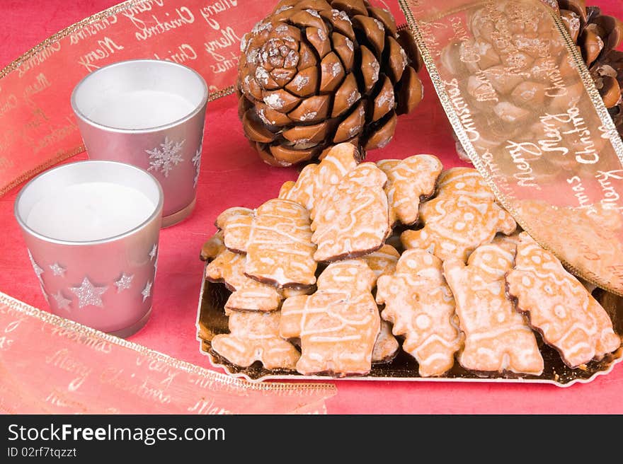 Christmas composition: gingerbread men, Christmas ribbon, pine cones and candles. Studio shot over red background. Christmas composition: gingerbread men, Christmas ribbon, pine cones and candles. Studio shot over red background