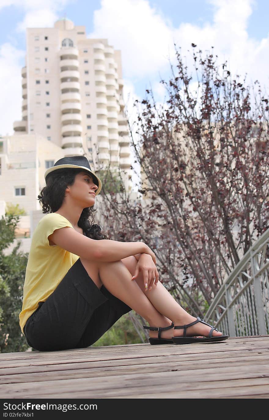 Beautiful young woman is sitting in a bridge in city-park