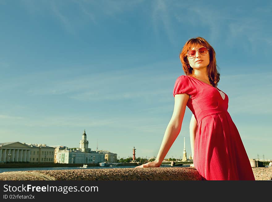 The young girl dreams on quay of the river with a kind on the bridge