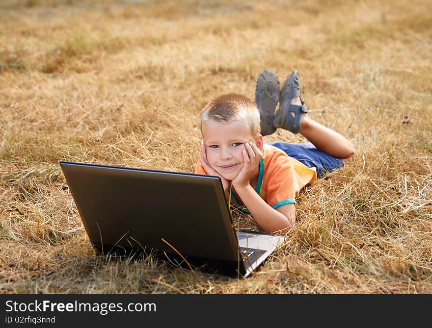 Young Boy Laying On Ground With Laptop