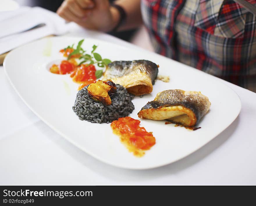 Fish fillet with black risotto and tomato relish