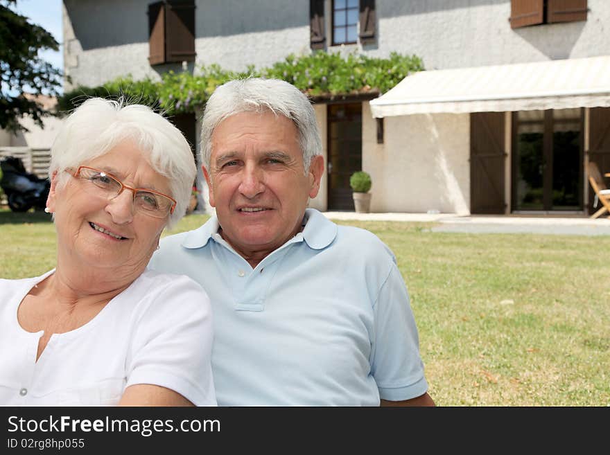 Senior couple sitting in front of a house. Senior couple sitting in front of a house