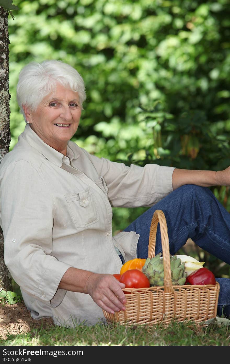 Elderly woman in garden with basket of vegetables. Elderly woman in garden with basket of vegetables