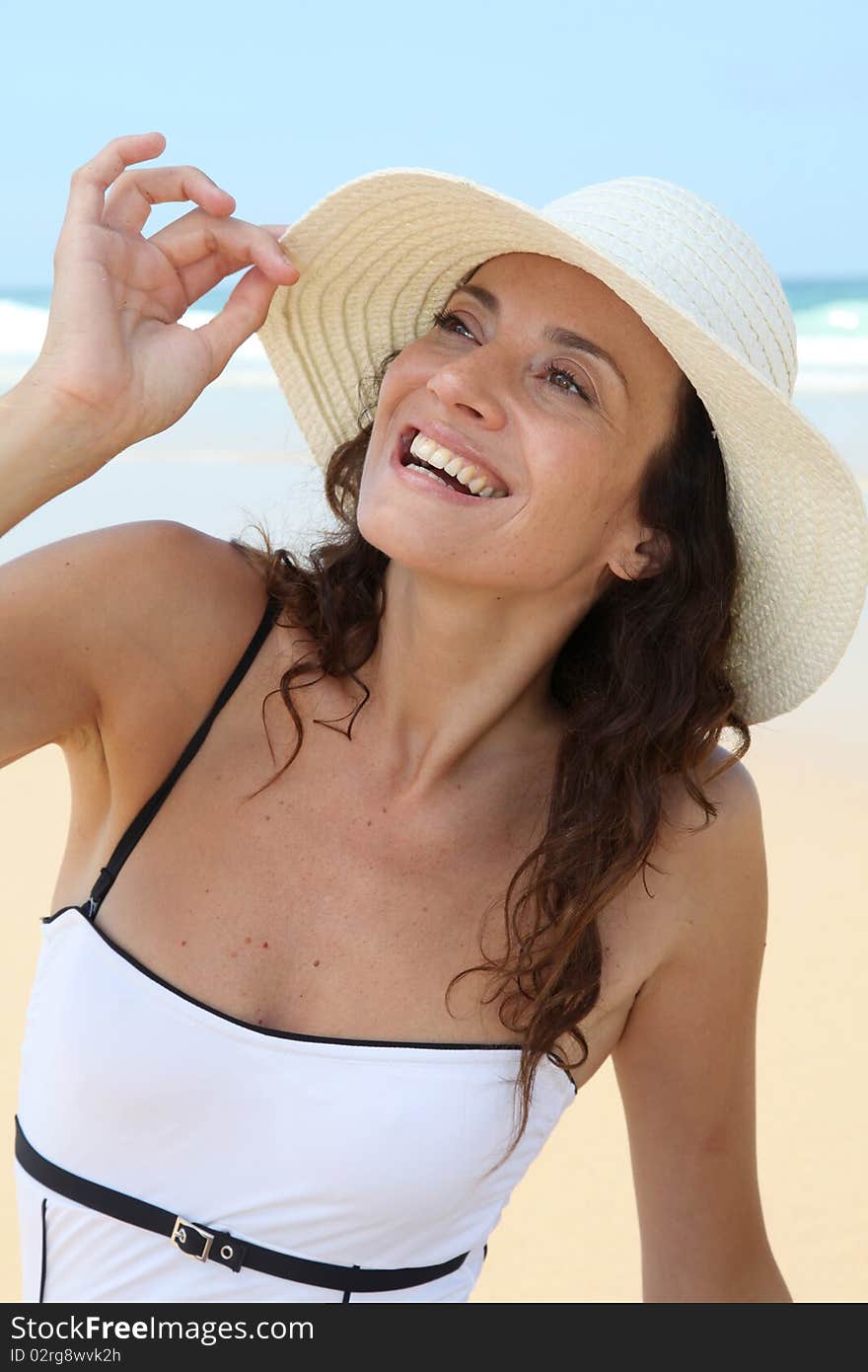 Beautiful woman sitting on the beach with straw hat. Beautiful woman sitting on the beach with straw hat