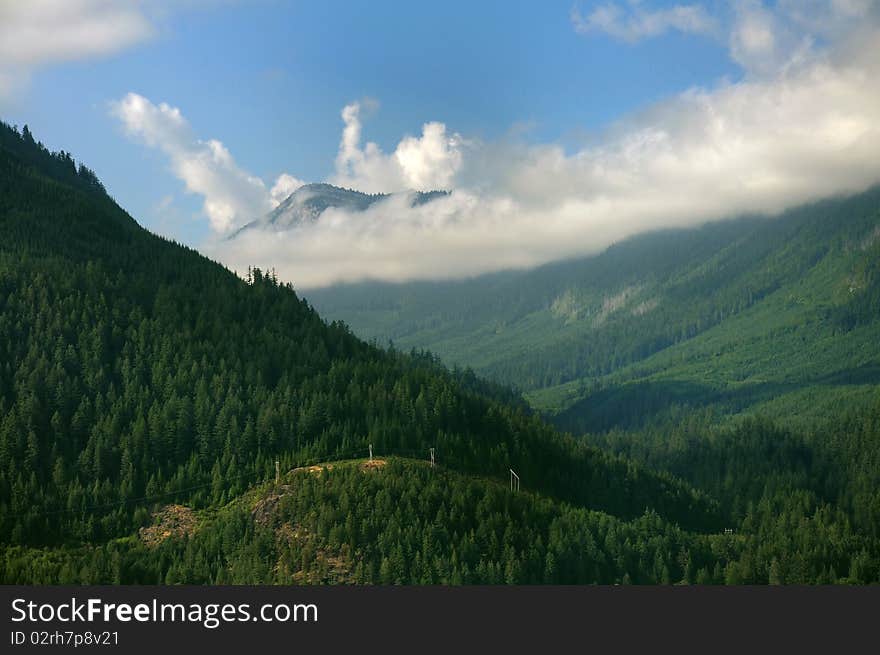 Clouds hovering over tree-covered mountains in a fine afternoon. Clouds hovering over tree-covered mountains in a fine afternoon