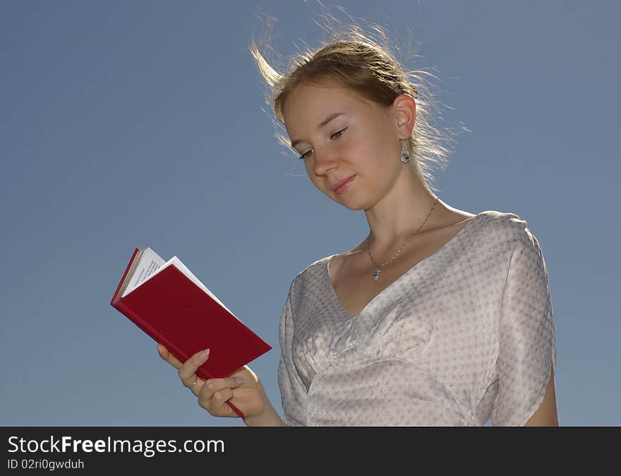 A girl reading a book with the red cover. A girl reading a book with the red cover