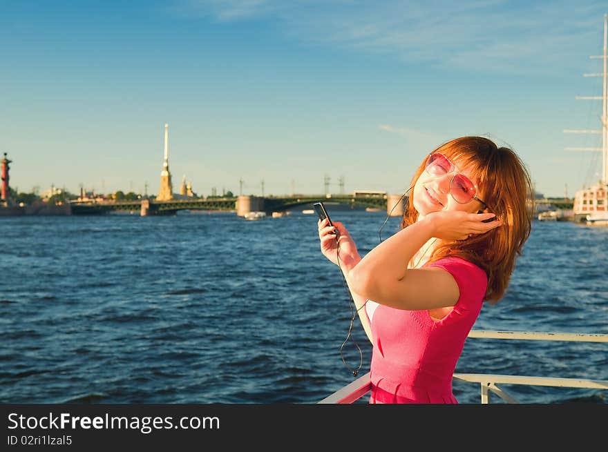 The young girl with a player in hands sings a song on a background of city