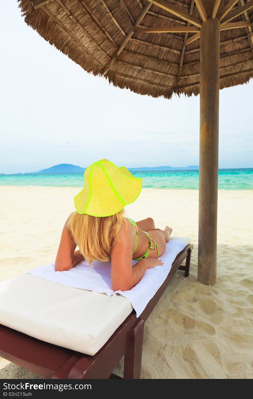 Young woman sunbathing on the chair near the ocean