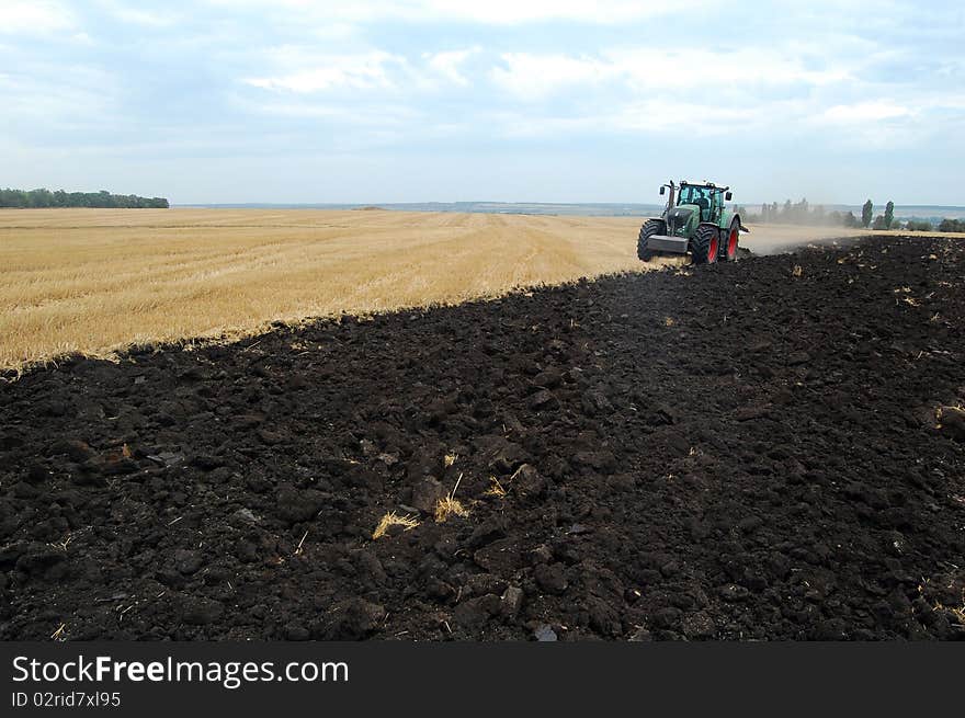 Plowing field by big plow and power tractor.