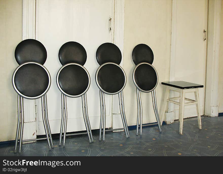 Folding chairs and stool against a white wall