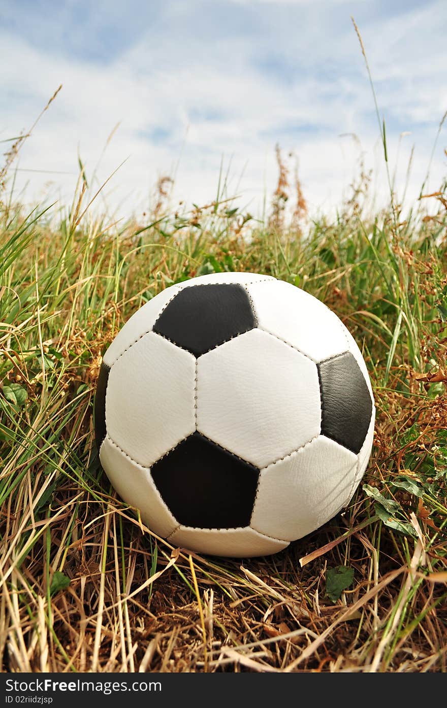 He skidded off the playing field and lies in the grass, traditional and classic round sports equipment for soccer, close-up. He skidded off the playing field and lies in the grass, traditional and classic round sports equipment for soccer, close-up