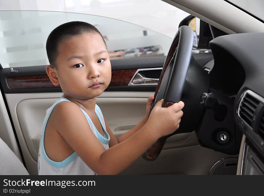 A Chinese boy inside a new car gestures to drive. A Chinese boy inside a new car gestures to drive.