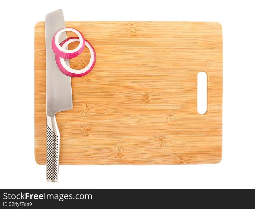 Slices of cut onion and a stainless chef's knife on a board. Slices of cut onion and a stainless chef's knife on a board