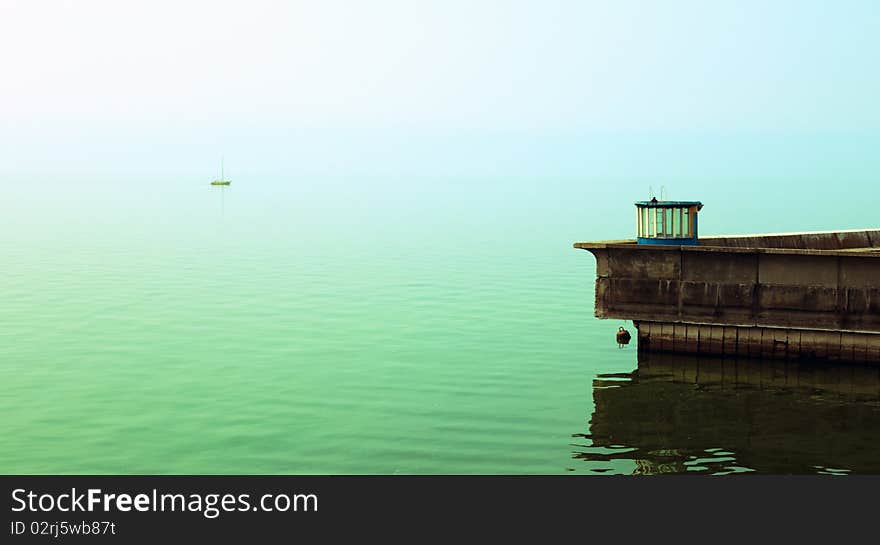 The yellow sailing boat sails from coast. The yellow sailing boat sails from coast