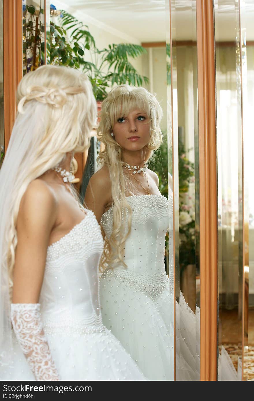 The beautiful bride looks in a mirror.