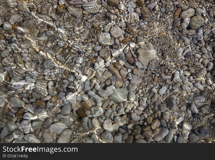 The shallow water of the Black Sea with scatter from the pebbles in the crystal clear water. The shallow water of the Black Sea with scatter from the pebbles in the crystal clear water