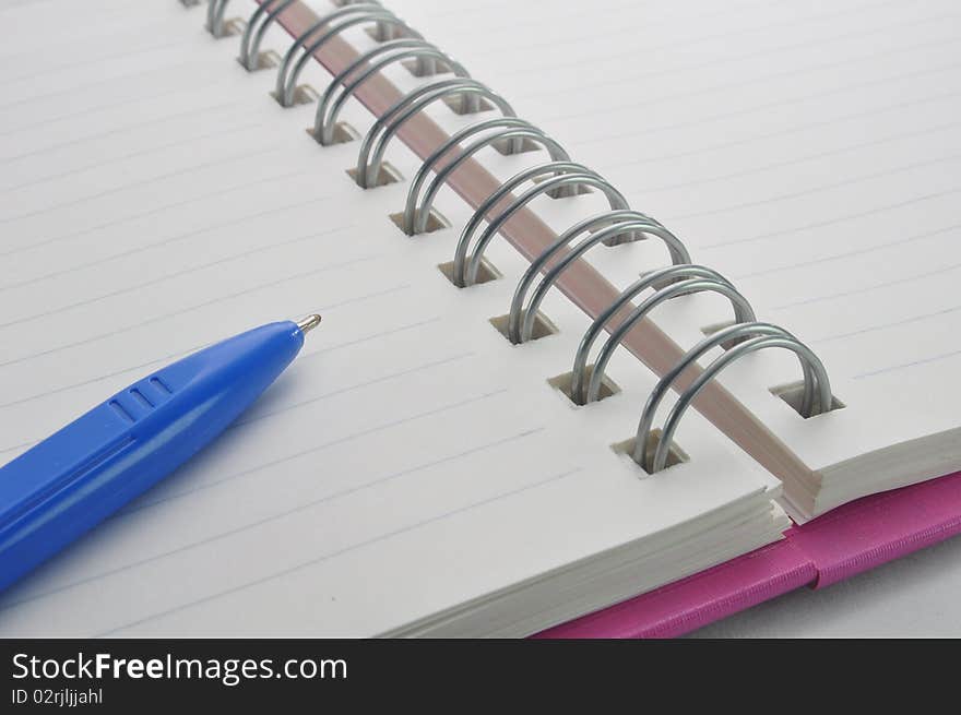 Notebook and blue pen in background. Notebook and blue pen in background