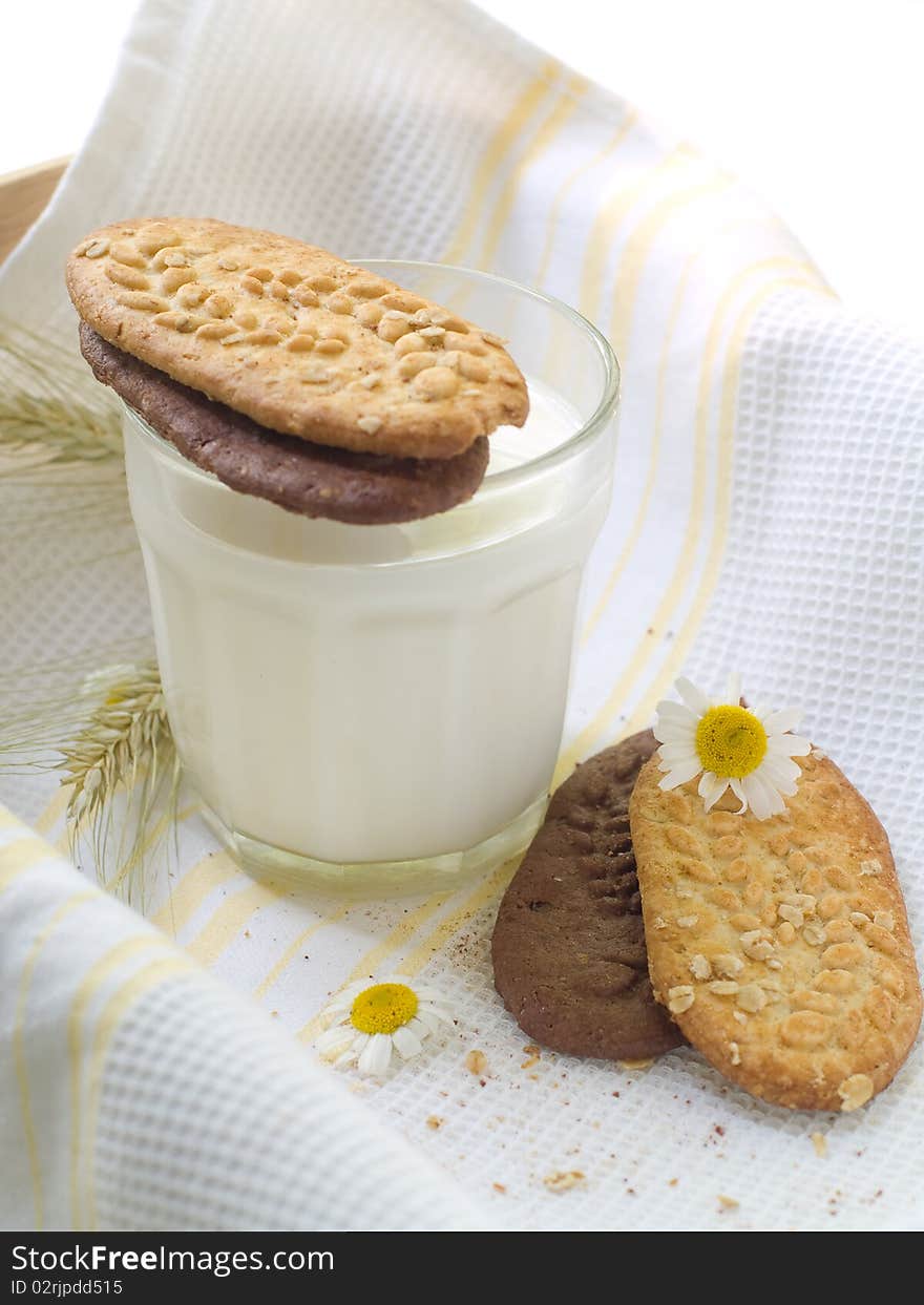 Glass of milk and cookies on light kitchen towel