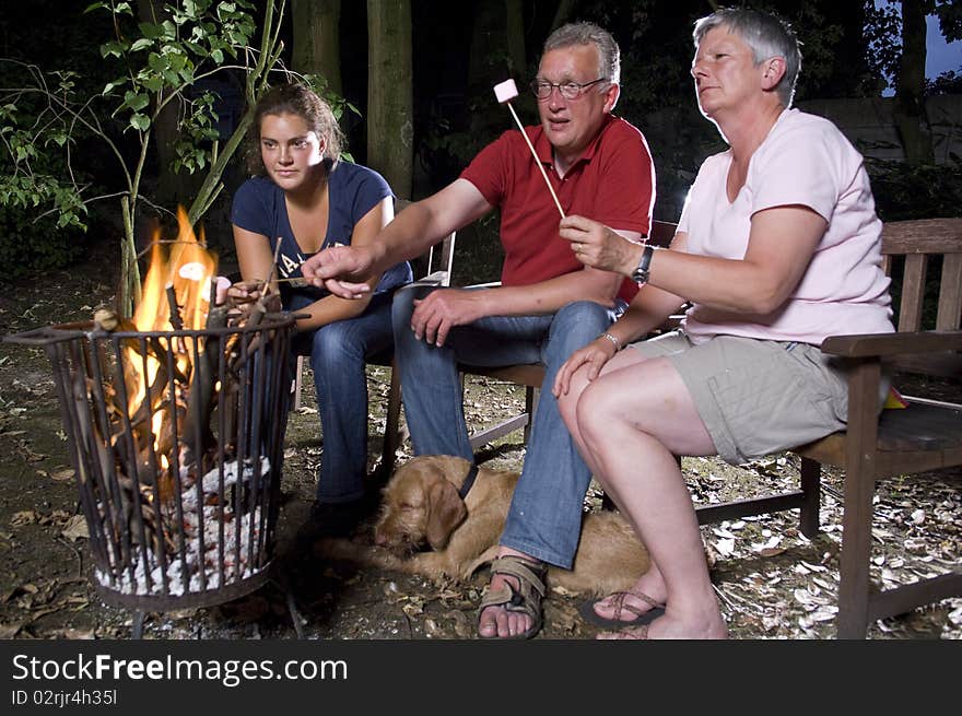 Family at campfire in the garden with marshmallows