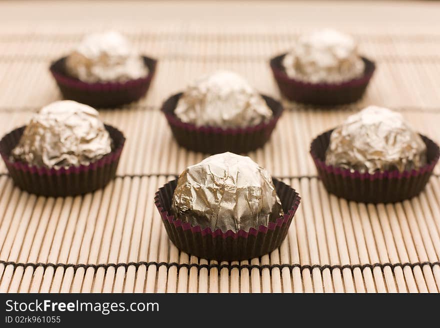 Group of choco candies in golden foil on table. Group of choco candies in golden foil on table