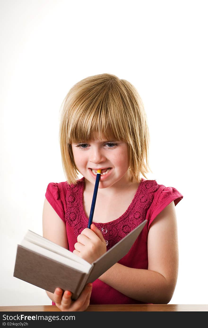 A vertical image of a cute little girl holding her diary and pencil and looking very thoughtful. A vertical image of a cute little girl holding her diary and pencil and looking very thoughtful