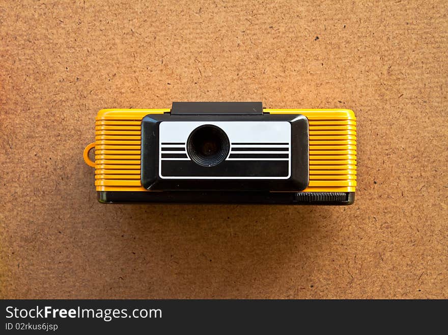 Retro yellow toy camera on wood board