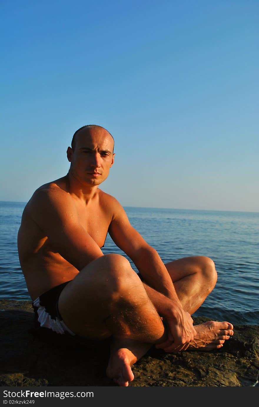 Man sitting on a rock contemplating the sea. Man sitting on a rock contemplating the sea