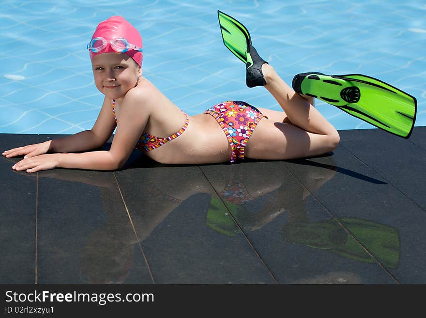 Little child in bathing cap, glasses, fins near sw