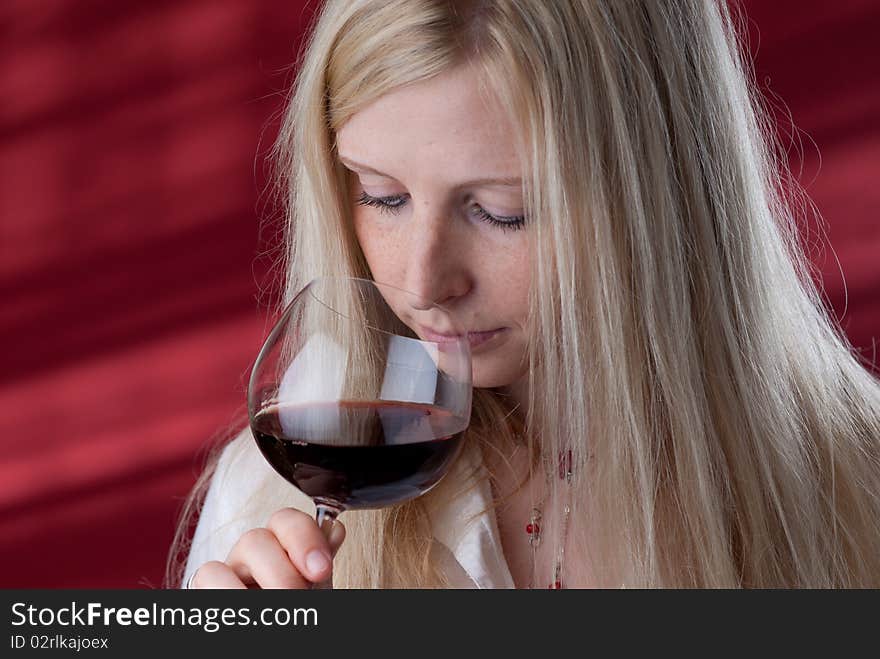 Portrait of a beautiful young woman with a glass of red wine, she is smelling. Portrait of a beautiful young woman with a glass of red wine, she is smelling.