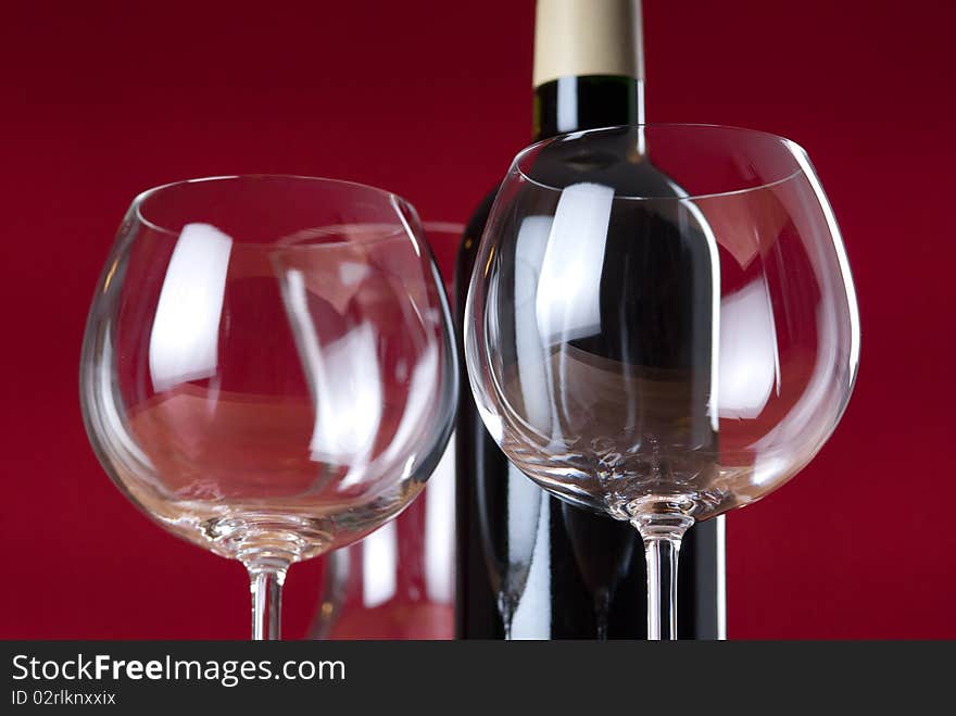 Detail of two wineglasses, red wine bottle and carafe with red background. Detail of two wineglasses, red wine bottle and carafe with red background.