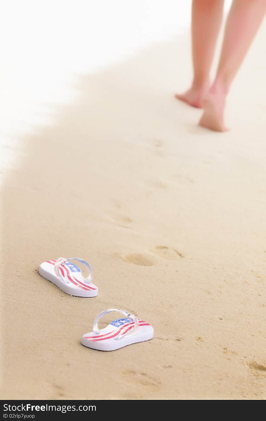 Woman's legs and pair of flip-flops on the beach. Focus on flip-flops. Woman's legs and pair of flip-flops on the beach. Focus on flip-flops.