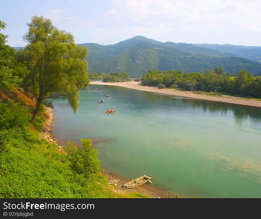 Group of unidentifiable people rafts in the rubber boats on green mountain river. Group of unidentifiable people rafts in the rubber boats on green mountain river.