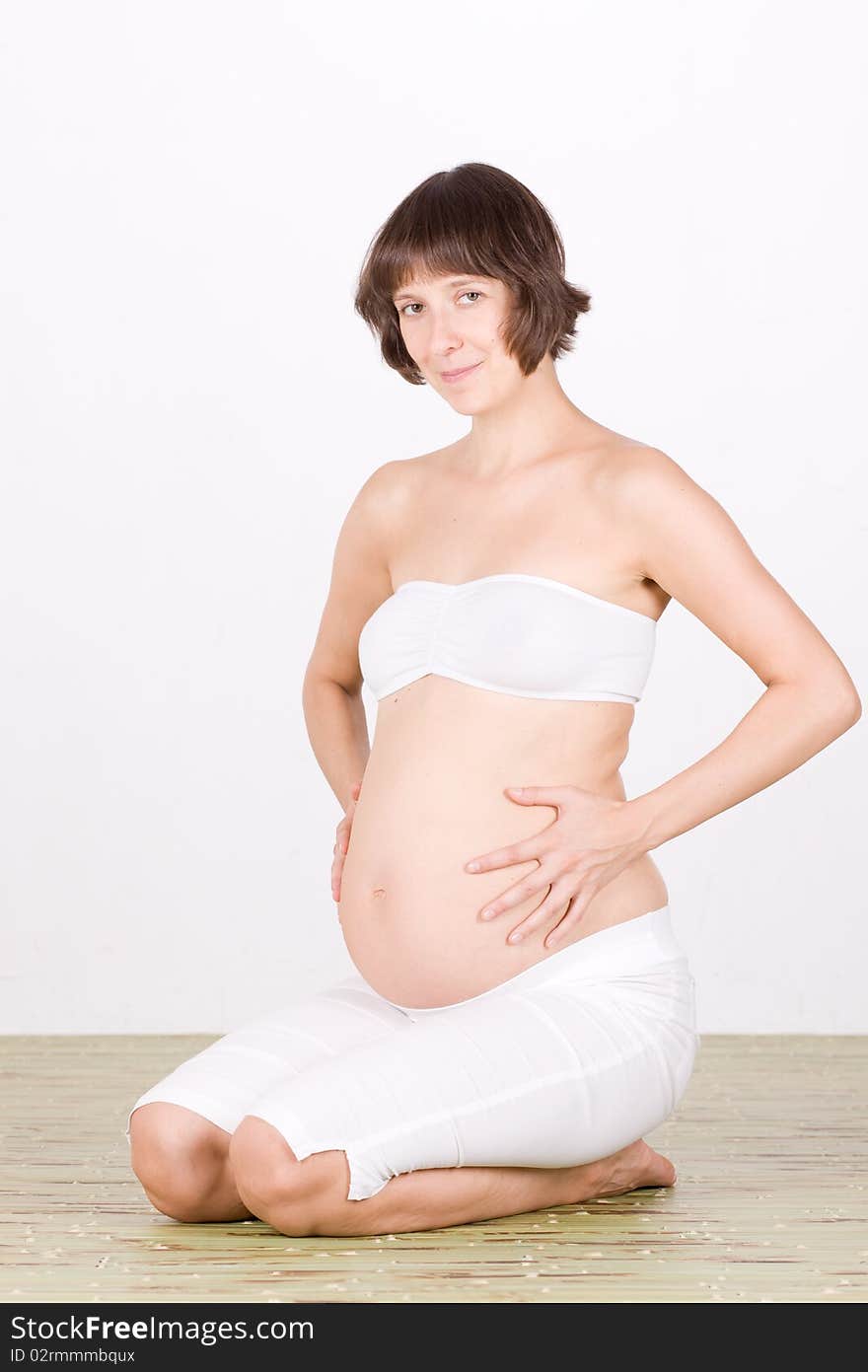 Pregnant woman sit on floor in studio