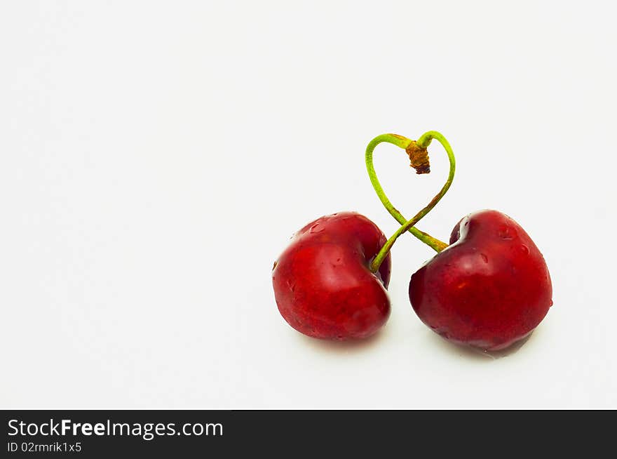 Pair of cherries were weaved by shanks in the form of heart isolated. Pair of cherries were weaved by shanks in the form of heart isolated