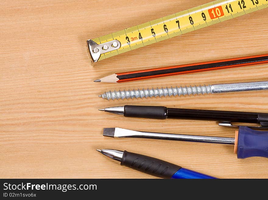 Pen, pencil and tape measure on wood table