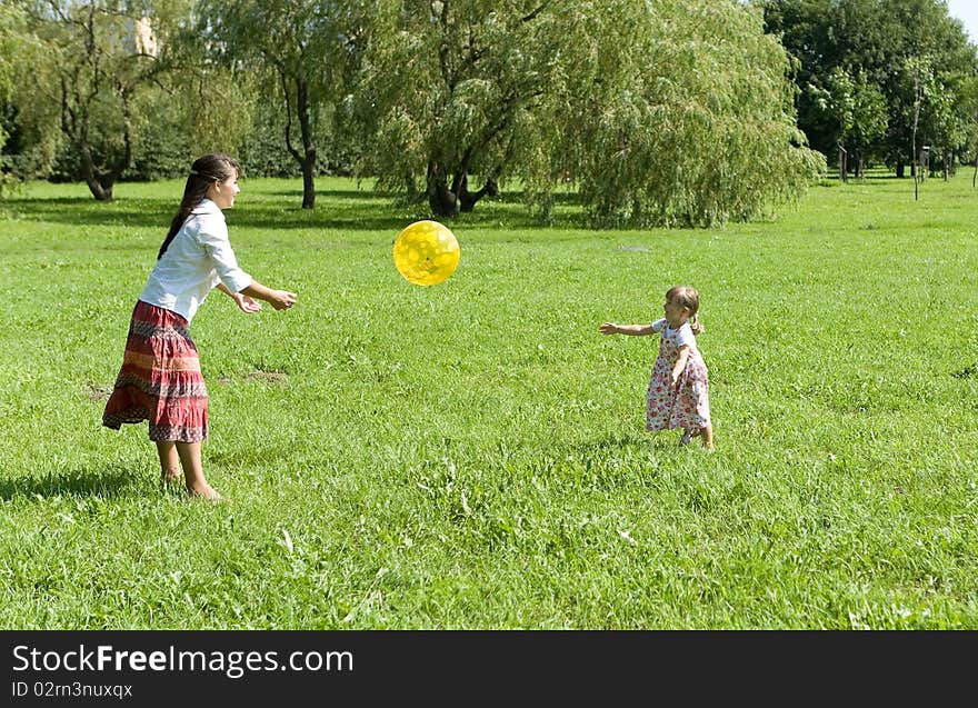 Mother and daughter playing ball on meadow. Mother and daughter playing ball on meadow