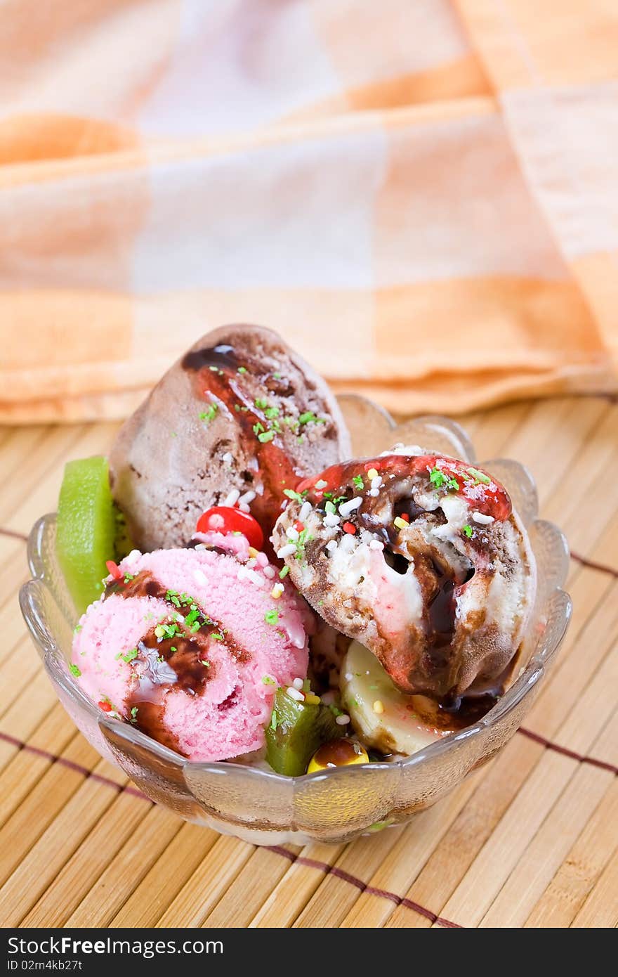 Glass cup with sweet icecream on wooden table top and a cloth on the background. Glass cup with sweet icecream on wooden table top and a cloth on the background