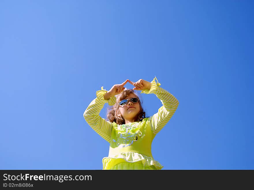 The girl in sun glasses draws in the dark blue sky fingers having lifted upwards hands. The girl in sun glasses draws in the dark blue sky fingers having lifted upwards hands