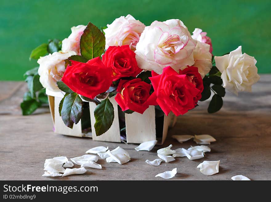 red and white roses are in a small basket