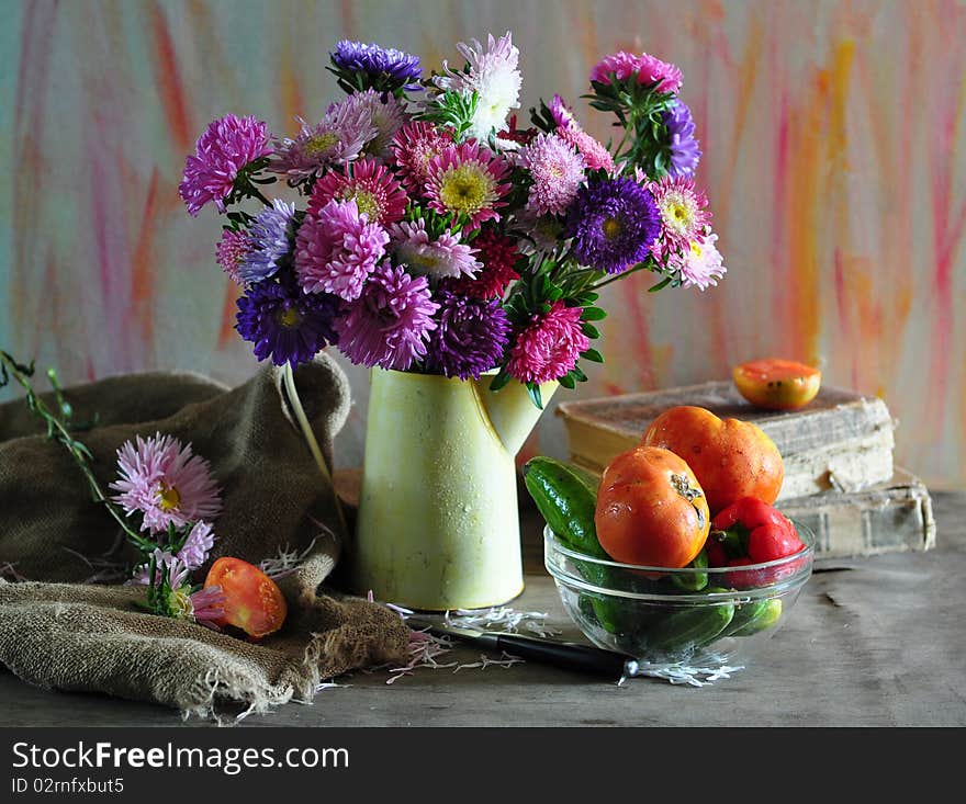 Bouquet of asters and dish with vegetables on an old table. Bouquet of asters and dish with vegetables on an old table