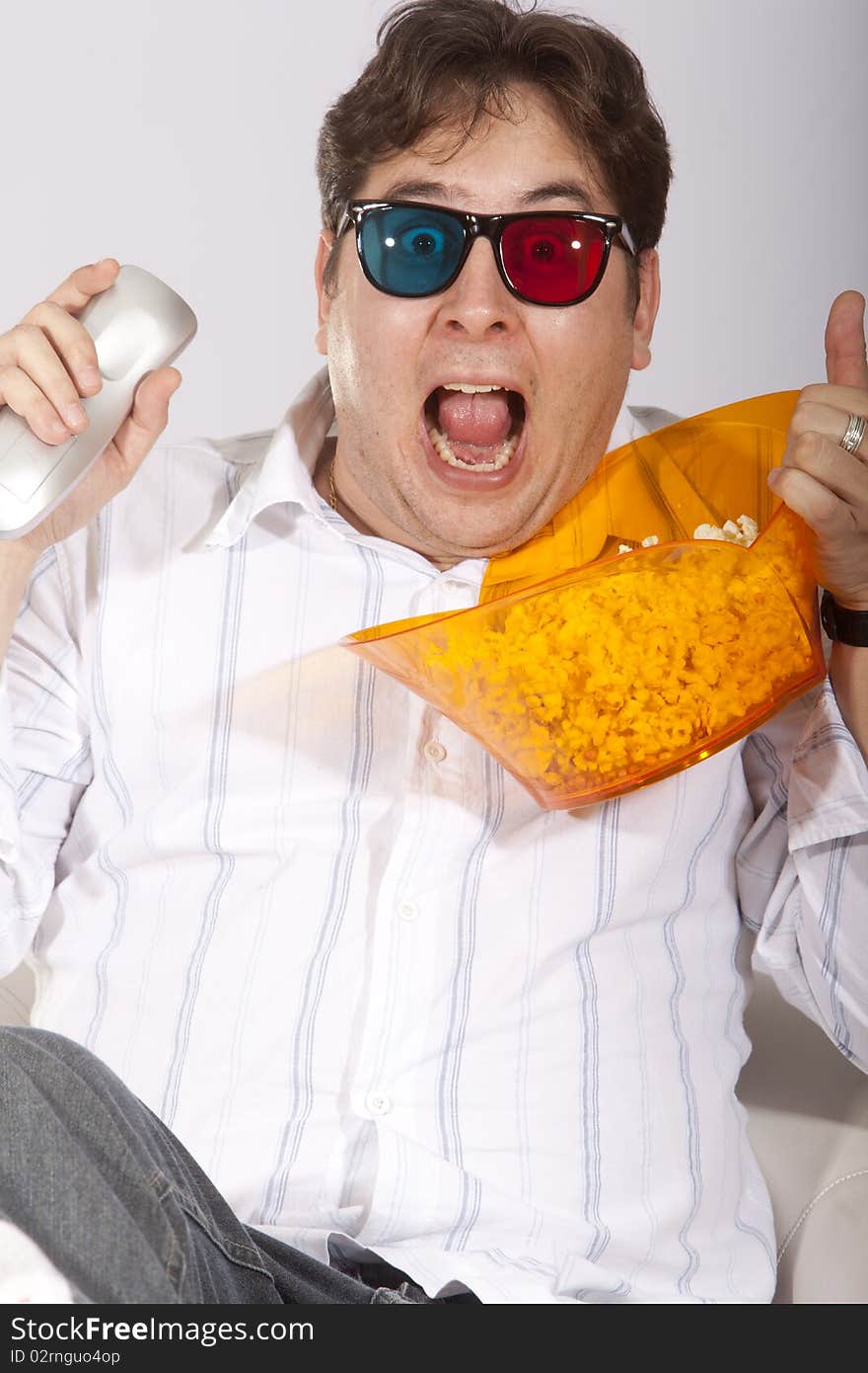 A young man watching a movie in 3D, with stylish 3D glasses and eating popcorn. A young man watching a movie in 3D, with stylish 3D glasses and eating popcorn.